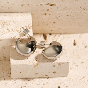 A pair of platinum Córdoba Hoop earrings lay atop a stone block to show off the wide, crescent-shaped curves and cylinder pushback closures.