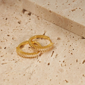A pair of Baguette Hoop earrings sits one atop the other, the light hitting them to show the defined shape of the baguette cut stones. 