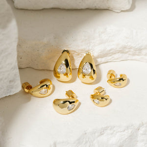 The three sets of earrings that make up the Amadora Hoop Trio are arranged on white, tiered stone slabs, the crystal accents on each sparkling brightly in the display light. 