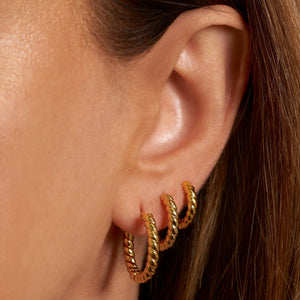The model wears the Bordeaux Hoop Trio in a sophisticated earring stack with vintage style. 