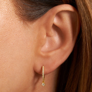 The row of crystal accents cascades from the model's ear, curving downward along the narrow golden hoop of the Bellagio Drop Hoop until they reach the larger crystal charm dangling gracefully at the base of the curve.  
