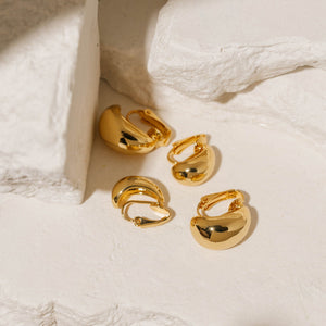 Gold Amadora Hoop Duo Clip-On earrings featuring a smooth, polished finish and a bold, curved design, displayed on a textured stone background. Elegant and versatile, these clip-on hoops by The Perfect Hoop offer a classic yet modern style