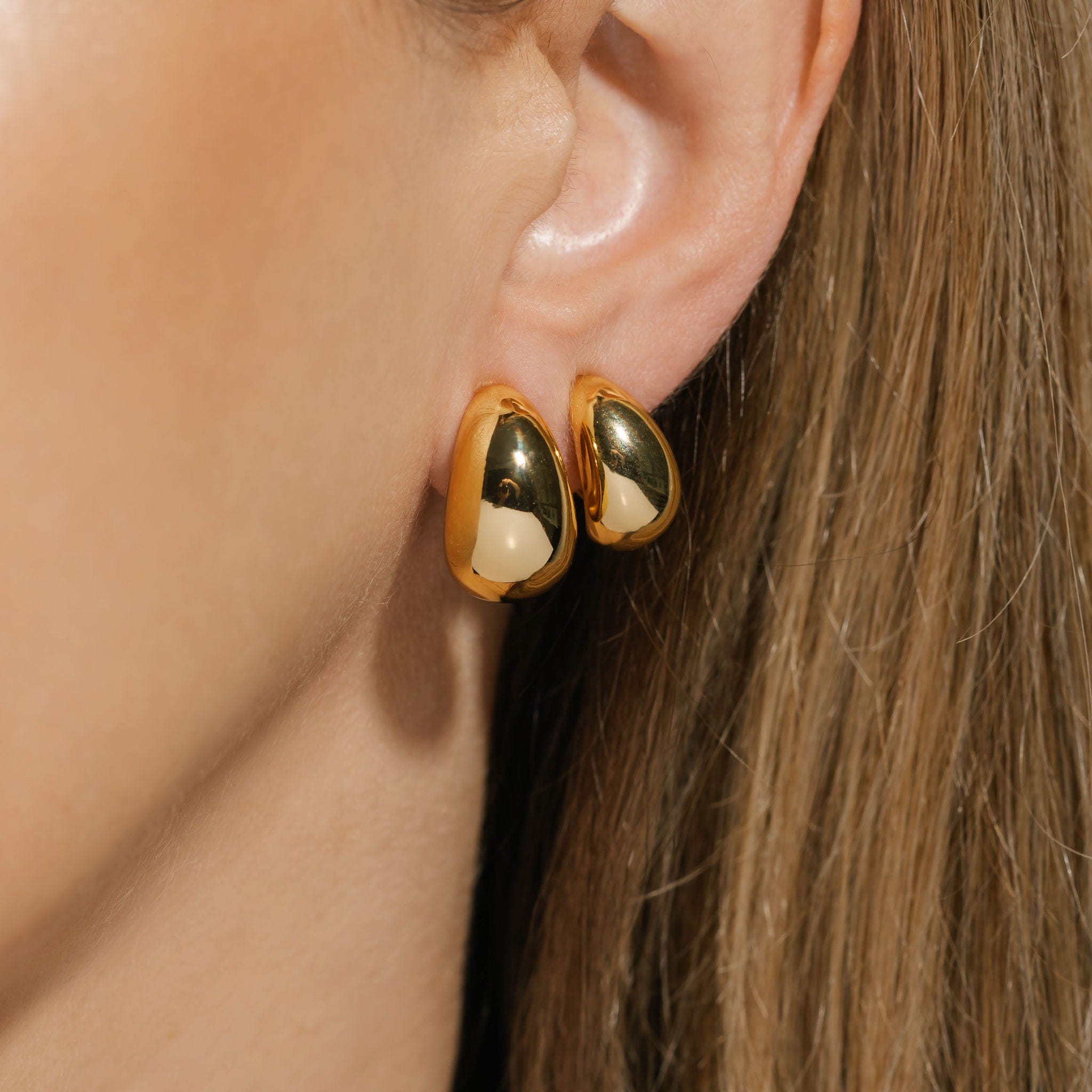 Model wearing the gold Amadora Hoop Duo Clip-On earrings, showcasing a smooth, polished finish with a bold, teardrop-like shape. These clip-on hoops by The Perfect Hoop add an elegant and sophisticated touch to any outfit