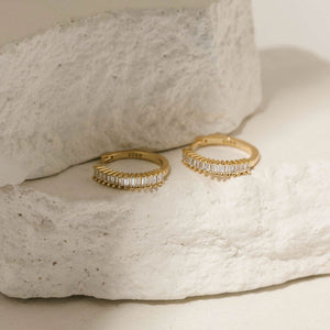 The Baguette Hoop – refined gold hoop earrings with a full row of baguette-cut crystals, photographed against white textured stone to emphasize their brilliance and modern structure, by The Perfect Hoop.