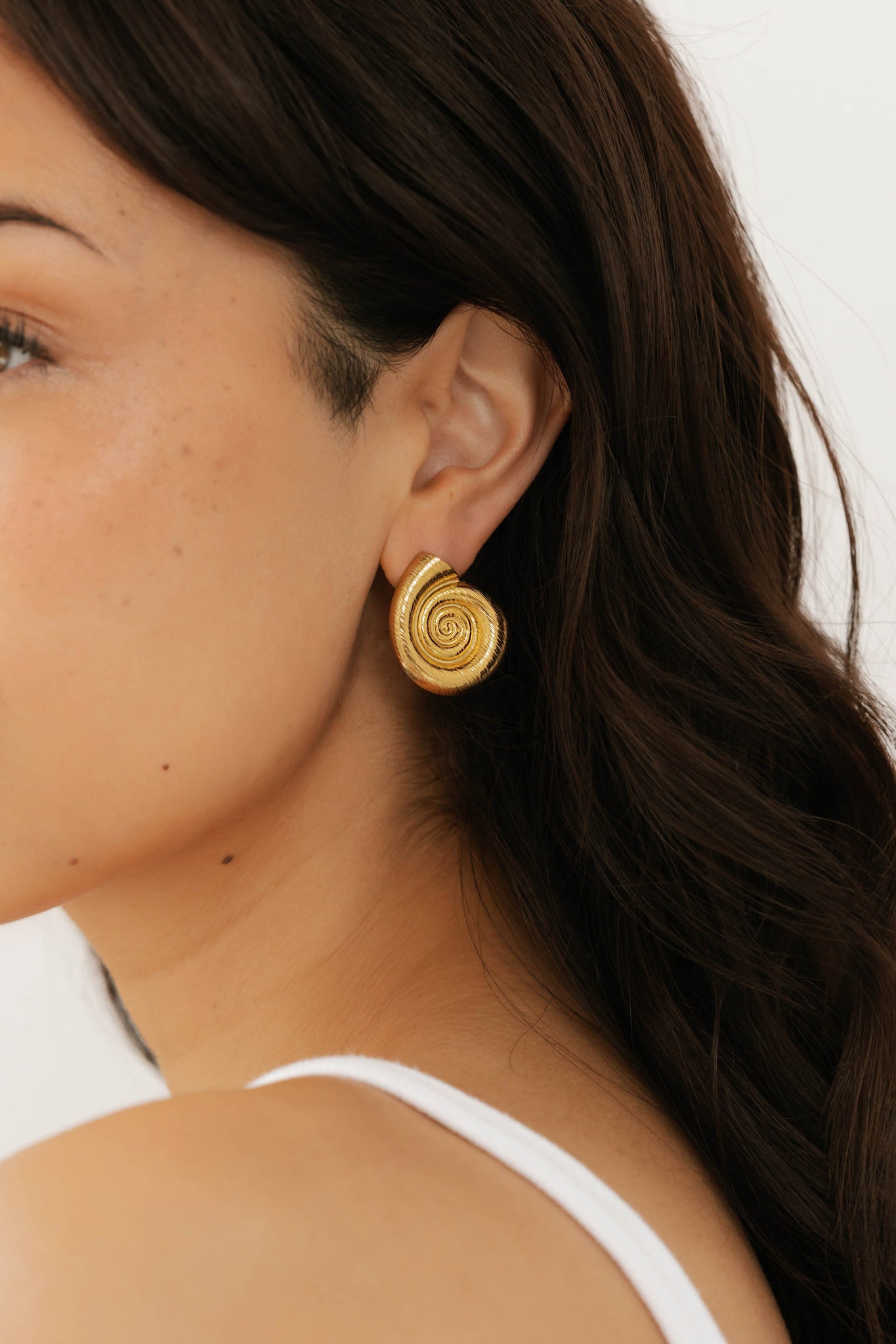 Side profile of model showcasing the elegant gold By The Sea Earring, styled with loose hair and a white tank top. By The Perfect Hoop.