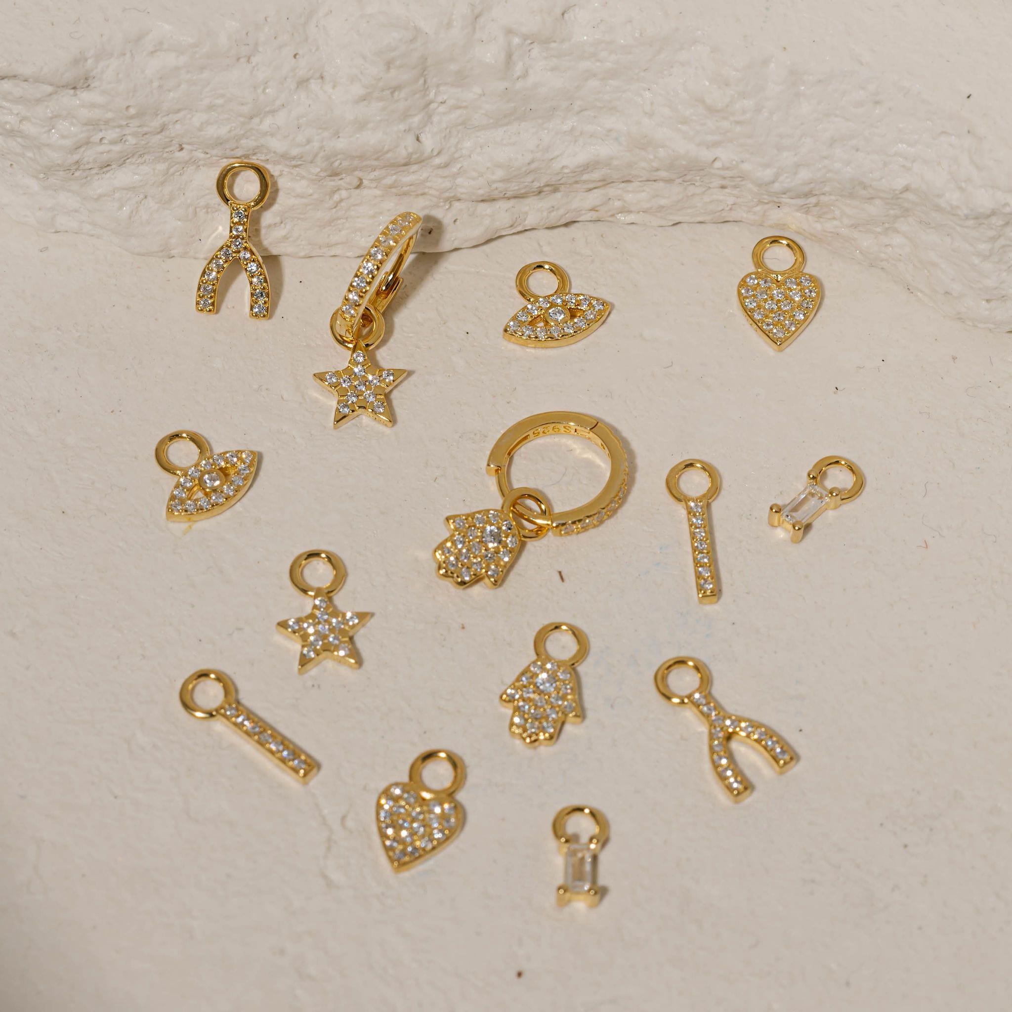 Collection of gold charms on a textured beige surface