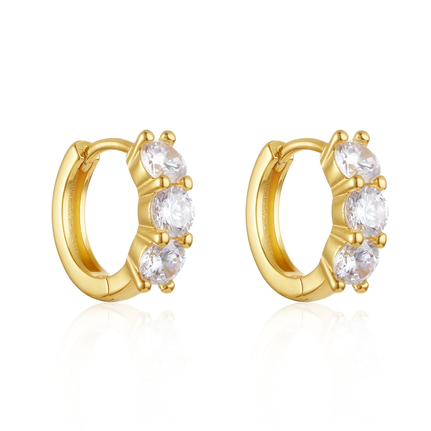 A pair of Cristaux Huggie earrings is displayed against a white background, the large crystal accents rising like mountains from the golden hoops. 