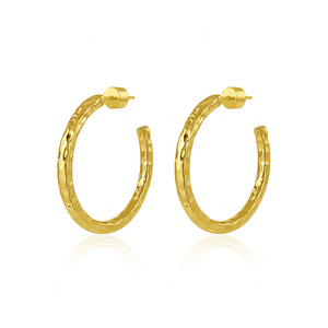 A pair of The Marbella Hoop 50 mm gold earrings with a hammered texture and polished cylinder backings, displayed on a seamless pure white background.