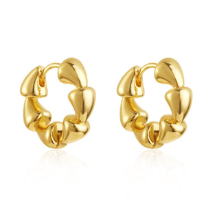 A pair of Nuvola Hoop earrings is displayed against a white background, the uniquely-shaped golden hoops glistening in the light. 