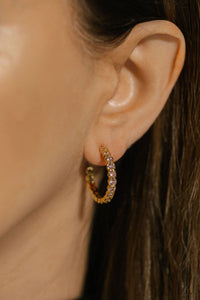 The Bambina Hoop earring adorns the model's ear, the pink crystals sparkling in the light.