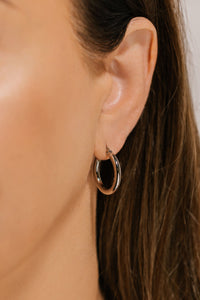  The sleek platinum finish on the Ravello Hoop Platinum earring shimmers as the earring is worn on the model's ear. 