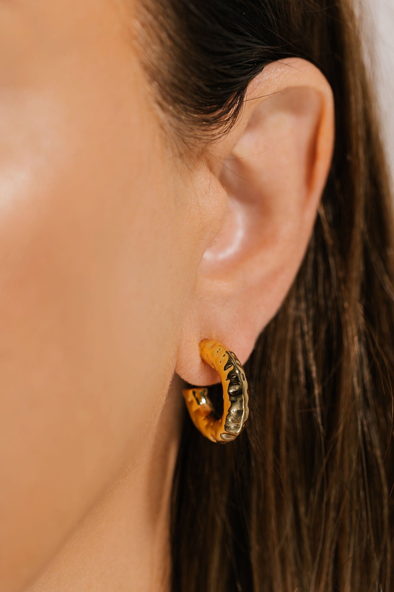 A close-up view shows the golden textured 20mm Marbella Hoop on the model's ear. 