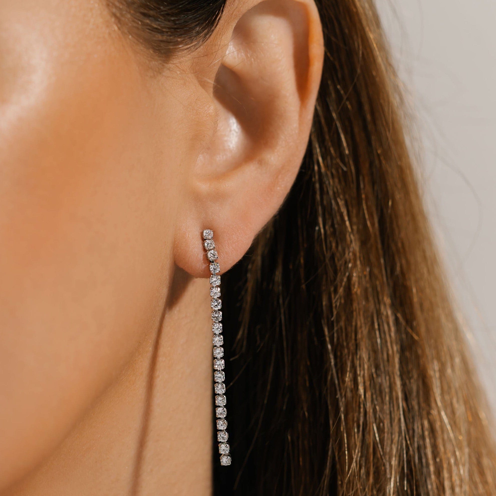 The crystal accents on the sterling silver Scintilla Dangle Hoop sparkle brightly as they fall from the model's ear.