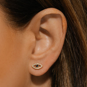An Evil Eye Cristallo Stud earring sparkles brightly on the model's ear as the deep blue of the center sapphire adds a touch of simple elegance. 