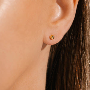 The golden Palma Stud earring adorns the model's ear. 