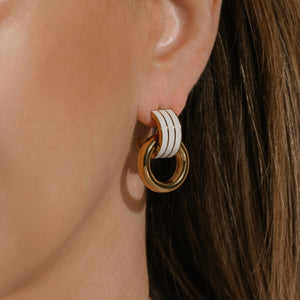 The Neroli Hoop earring adorns the model's ear, the white stripes cascading down as the golden hoop is suspended from their curve. 