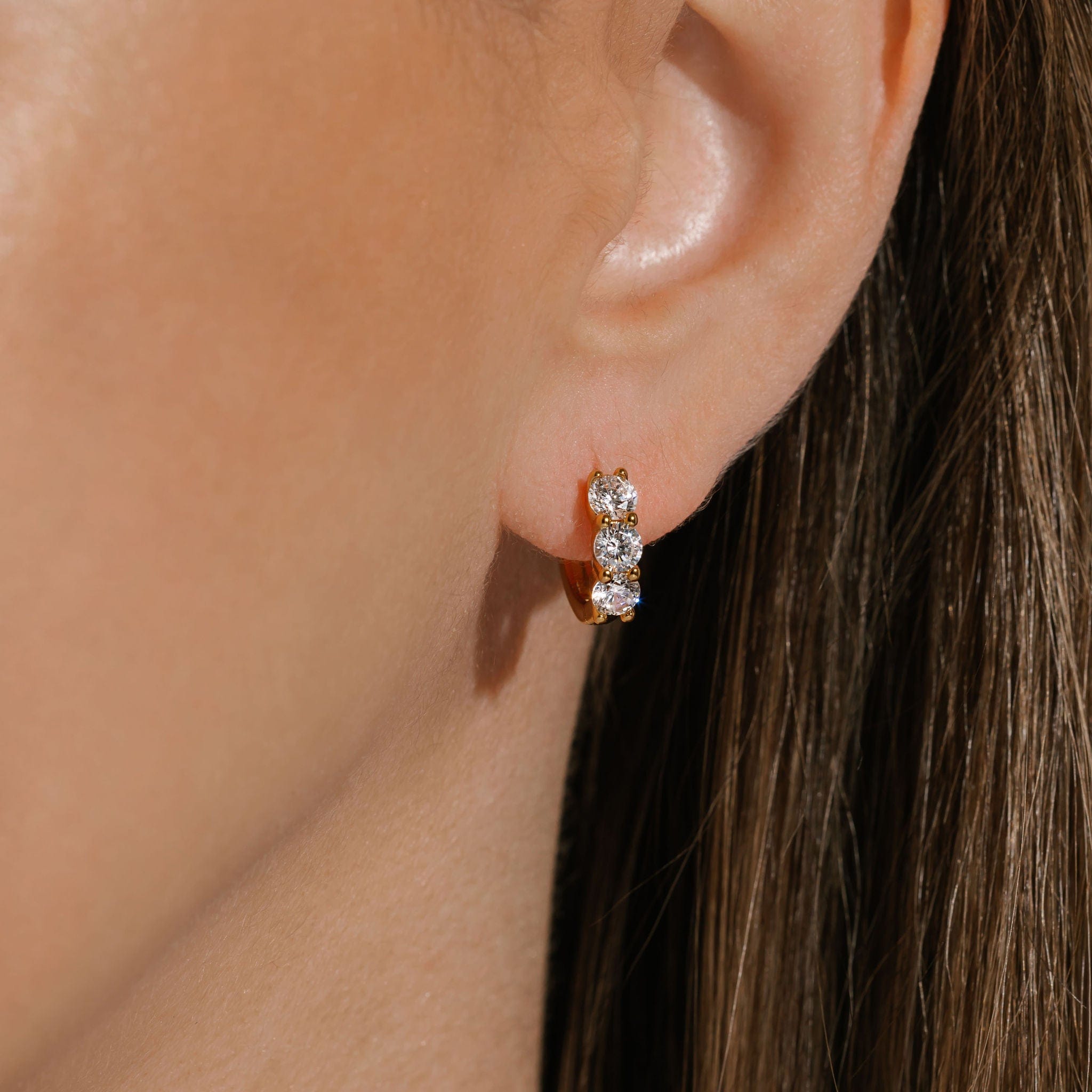 The Cristaux Huggie earring's bold crystal accents sparkle brightly on the model's ear. 