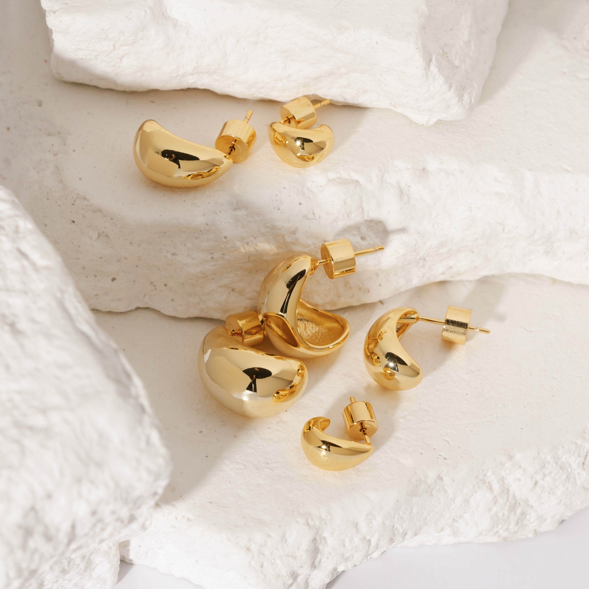 The three pairs of earrings that make up the Amadora Hoop Trio earring set lay on tiered stone slabs.