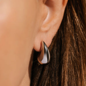 The sleek, platinum face of the Moda Hoop Mini has a polished sheen as it adorns the model's ear. 
