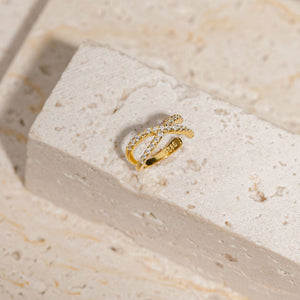 The Traverse Cuff sits on a stone block, the crystal accents sparkling atop the crossed front curve of the earring. 