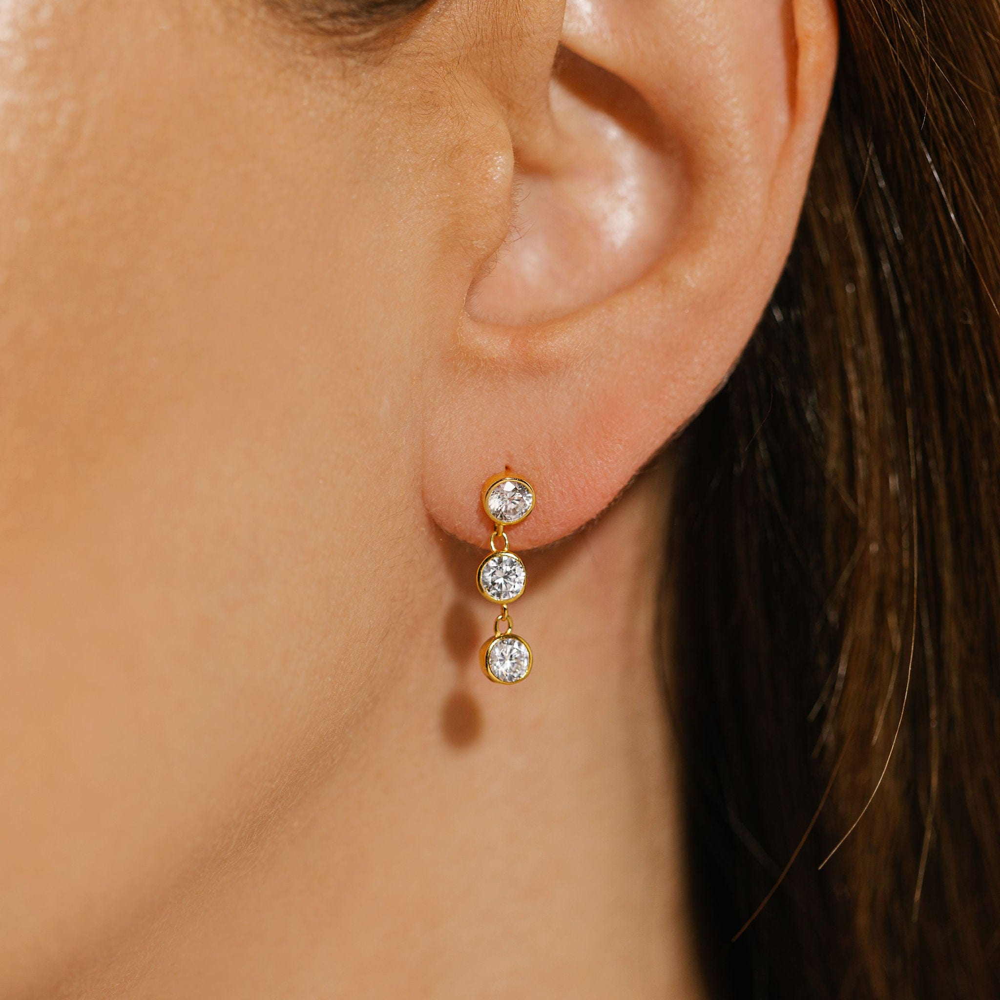 The three sparkling crystals of the Coquille Strand Stud earring gracefully trail downward from the model's ear. 