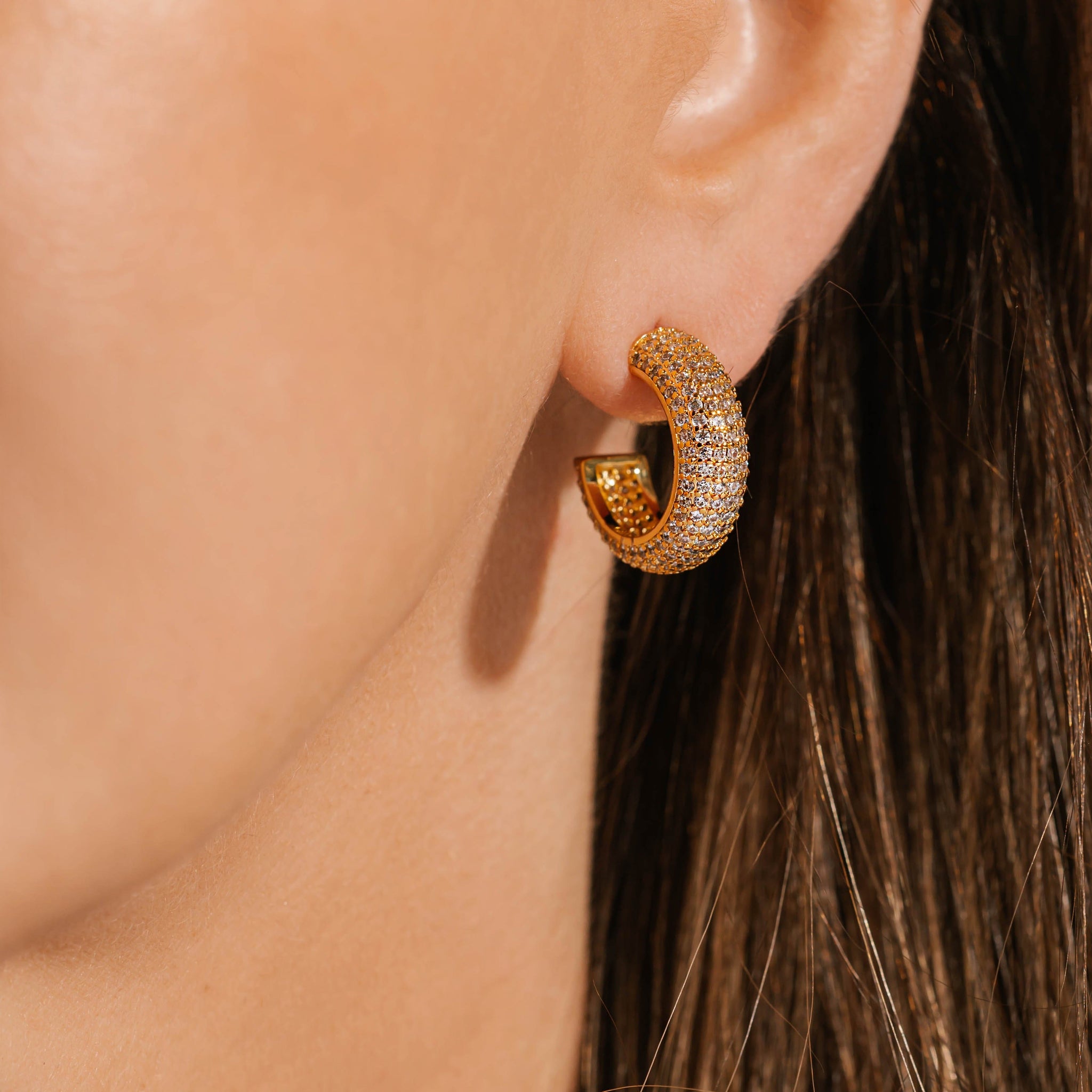 The model's ear is illuminated by the rows of crystals decorating the Siena Hoop Pavé earring that she is wearing. 