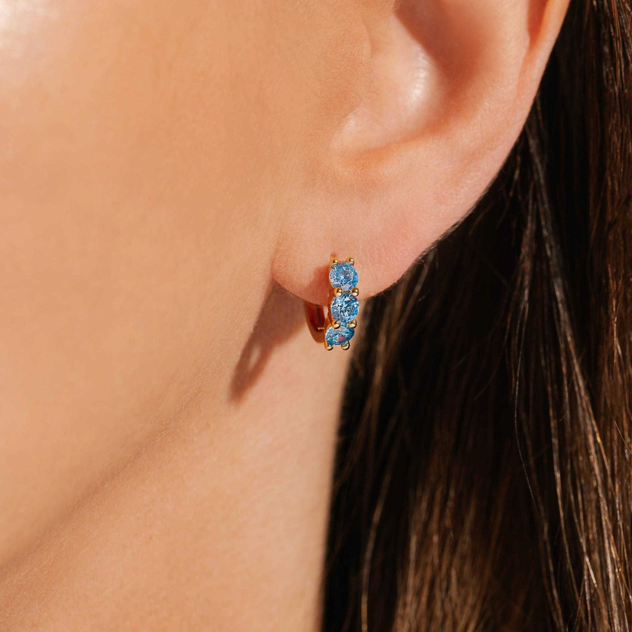 The three blue crystals that adorn the front of this Cristaux Huggie gracefully cascade from the model's ear. 