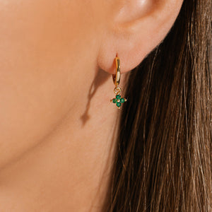 The golden ring and green clover-shaped charm of the Clover Drop Hoop-Verde create a dazzling accent on the model's ear. 