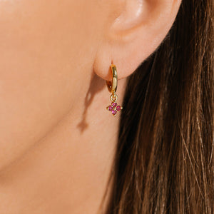 The Clover Drop Hoop-Fuchsia is a delicate accent on the model's ear. 