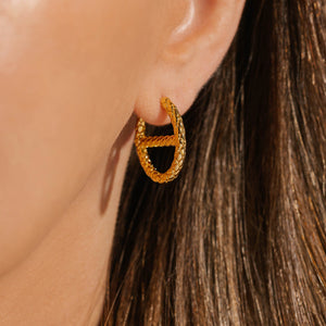 A close up view of the Jolie Hoop on the model's ear shows its textured face and stylish center bar.