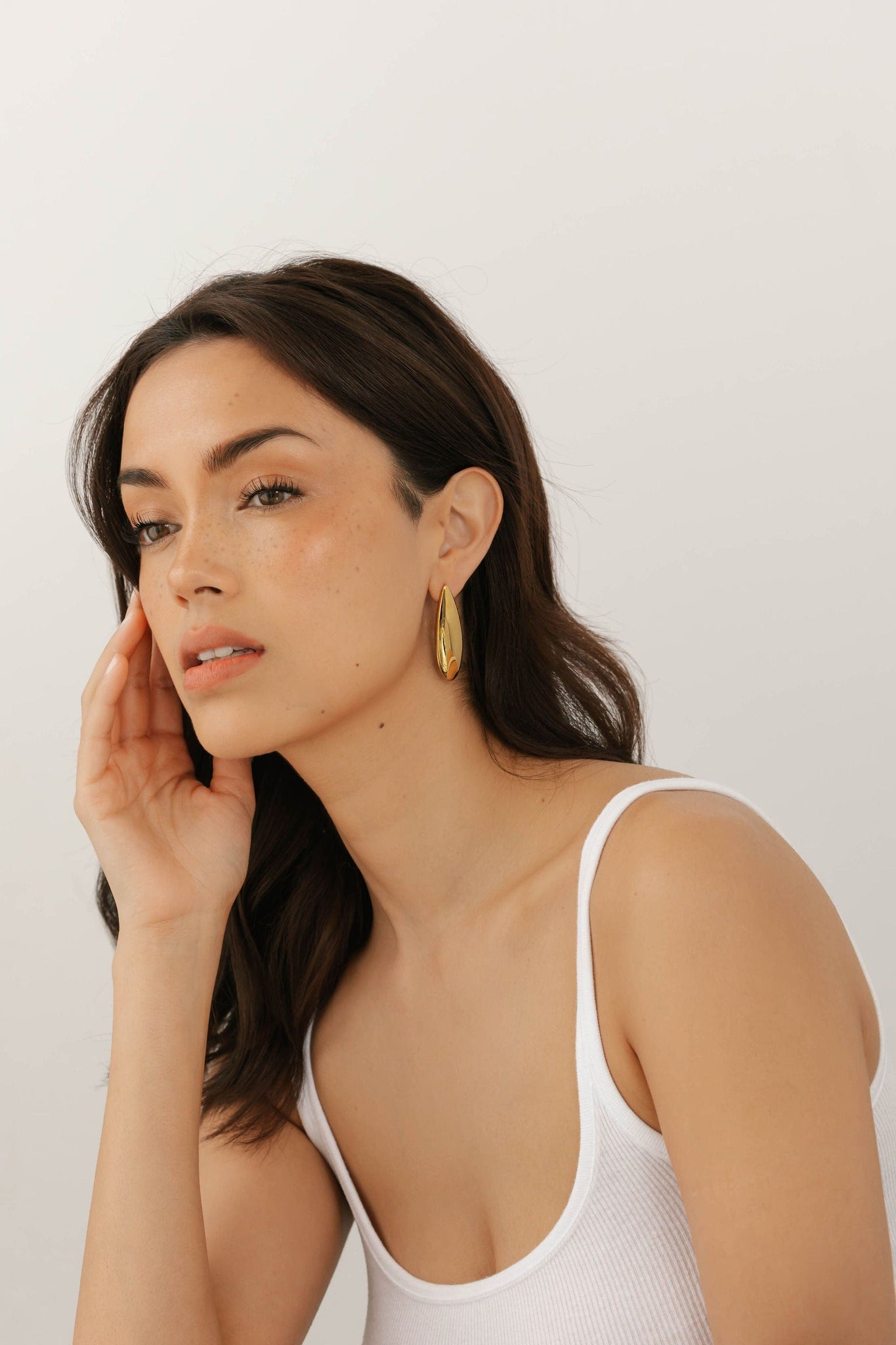 Full profile of The Perfect Hoop Lotus Earring on model, styled with hair down to emphasize the dramatic golden teardrop silhouette.