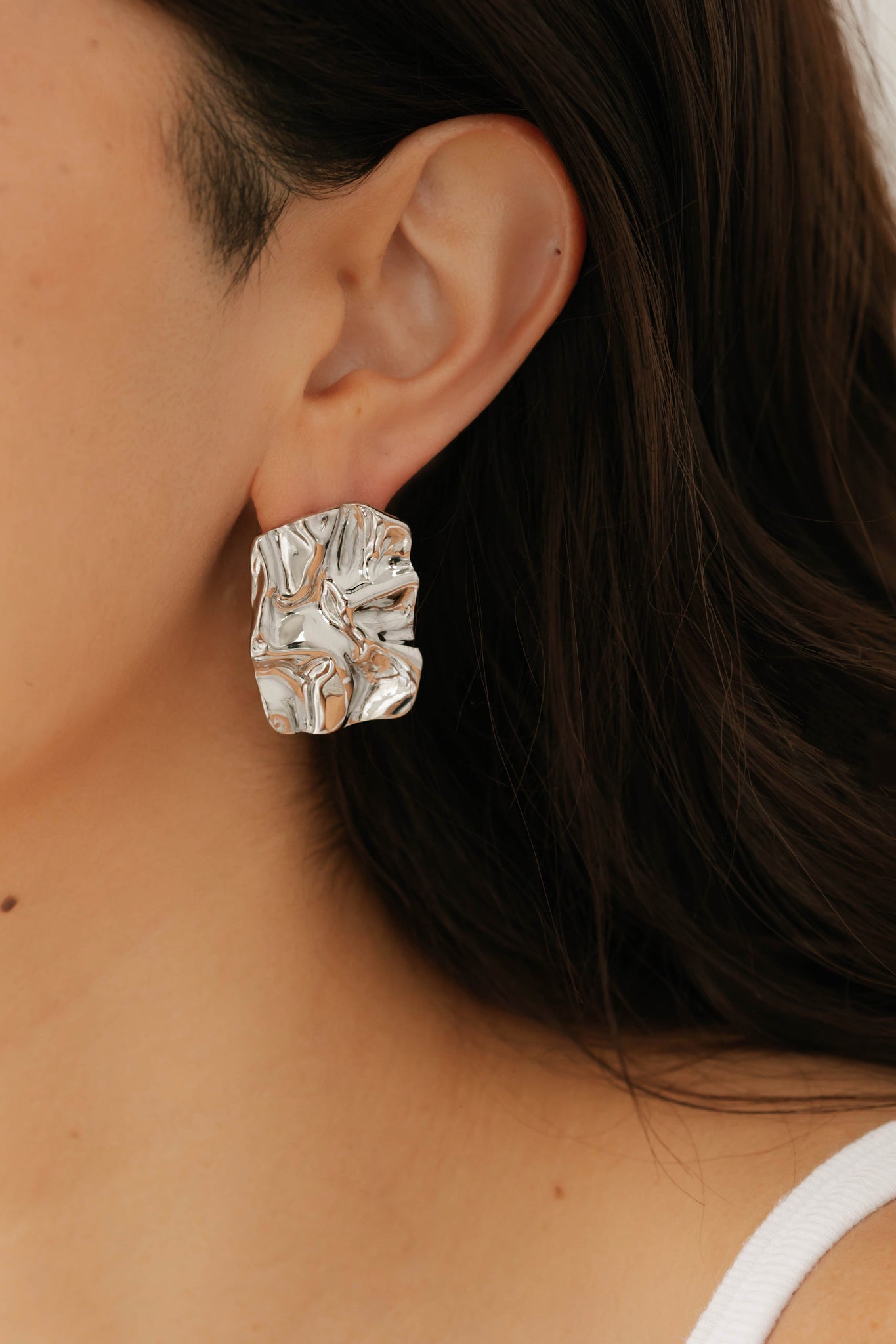 The Perfect Hoop Soleil Hoop in silver worn on model, showcasing sculptural, high-shine texture against dark hair and warm skin tone.