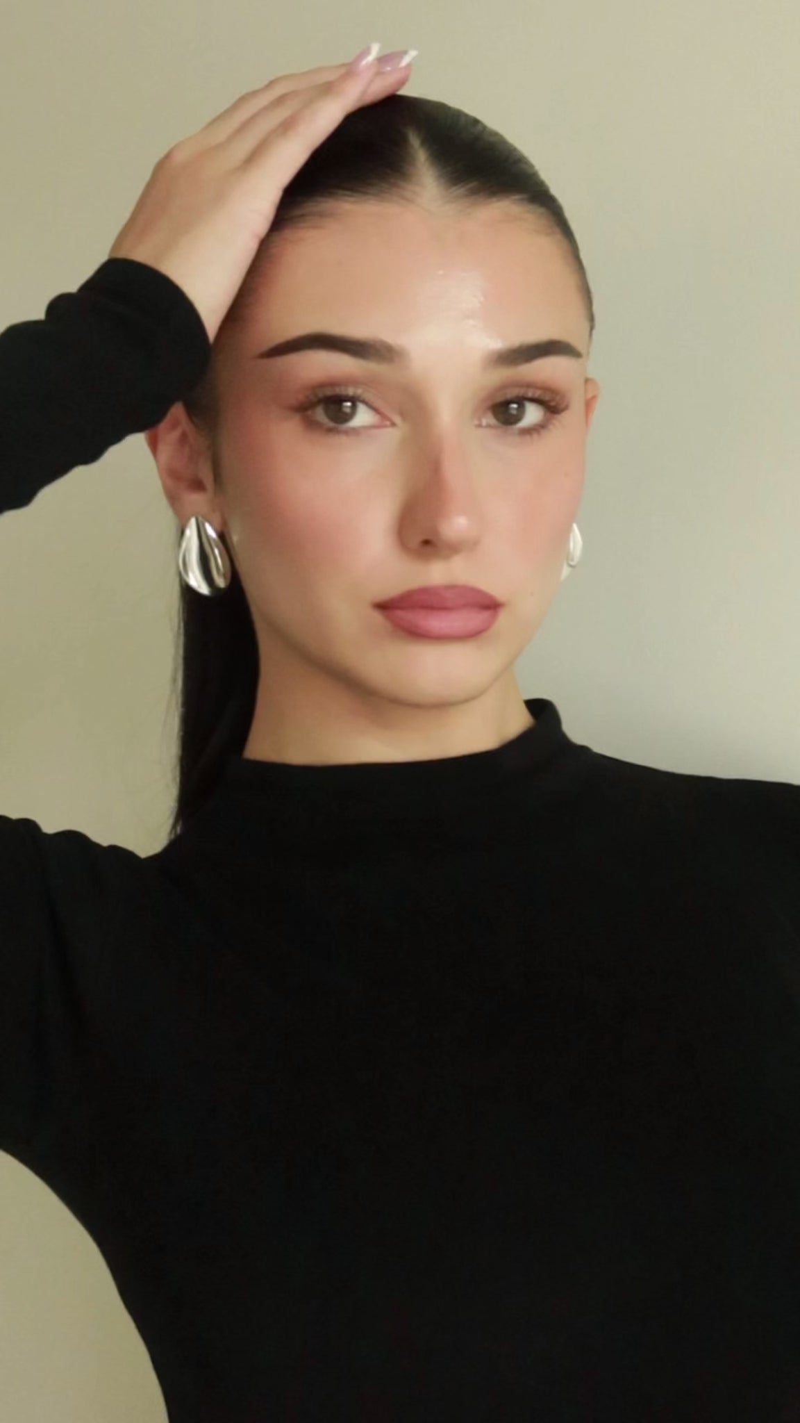 Model wearing The Perfect Hoop’s Harlow Earring in silver with a sculptural twist design, styled with a sleek ponytail and black turtleneck against a neutral backdrop.
