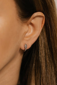 A close-up view of the Veleno Huggie Platinum earring shows how the snake seems to bite the model's lobe as the earring wraps around it. 