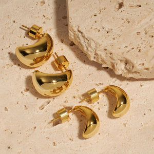 The four open hoop earrings of the Amadora Hoop Duo lay on a stone counter. 
