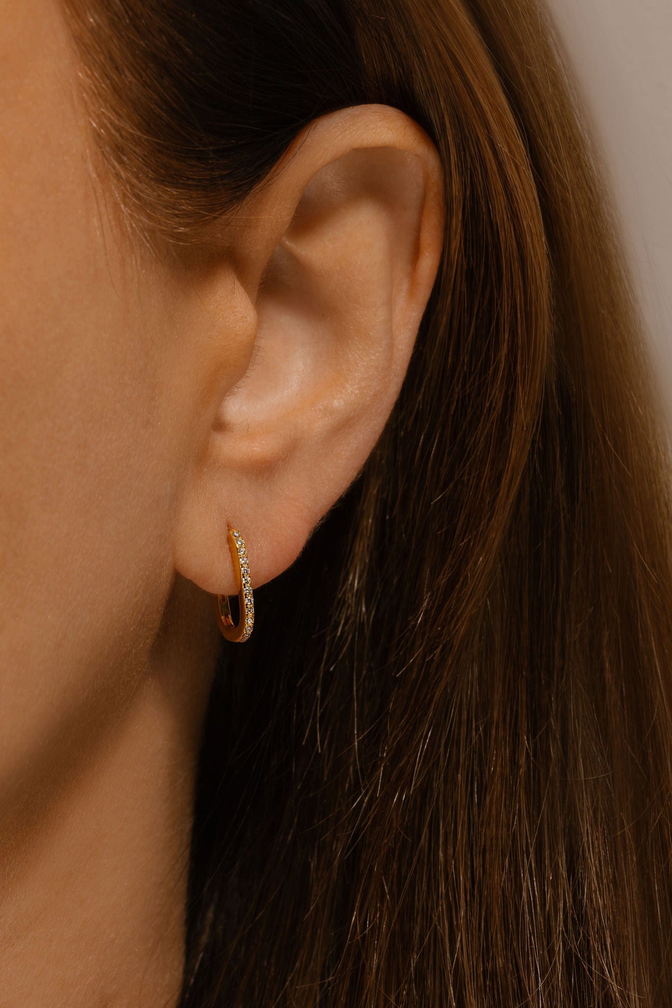 The model wears the Positano Scintilla Huggie, the crystal accents dazzling in a vertical row on her ear. 