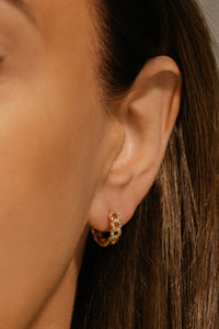 The crystal accents adorning the Valencia Huggie sparkle as the chain-link hoop curves around the model's ear lobe. 