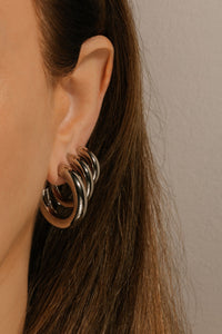 The model wears the Perfect Hoop Trio Platinum set in an elegant earring stack. 