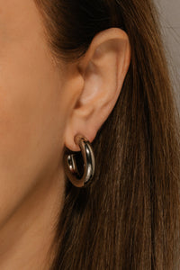 A close view shows the sleek Perfect Hoop Platinum earring as it's worn on the model's ear. 